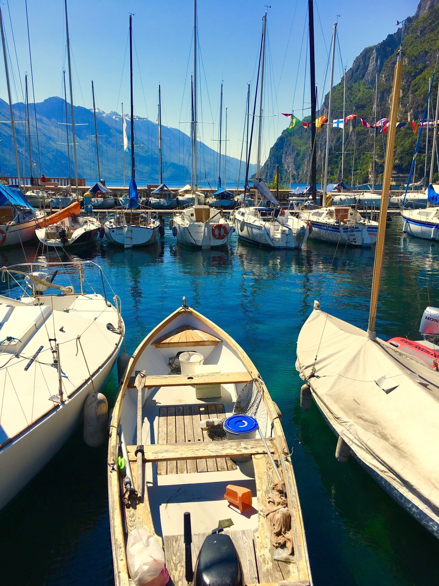 A marina with several boats docked, surrounded by mountains and clear blue water.