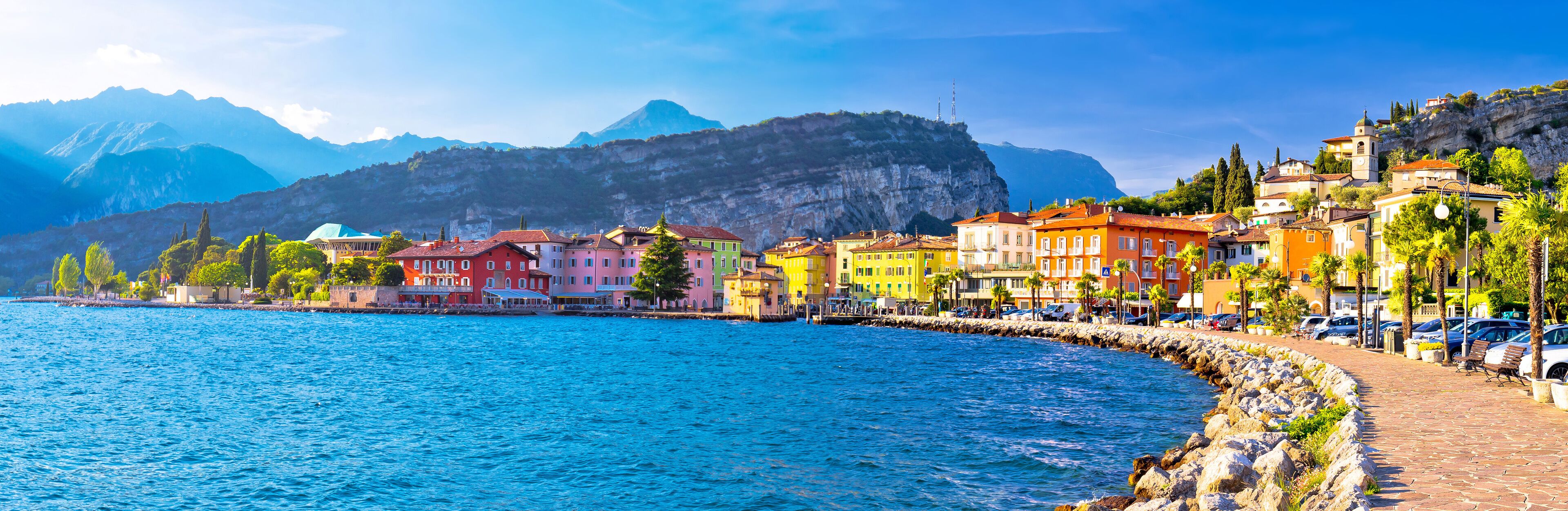 A coastal town with colorful buildings, a rocky shoreline, and mountains in the background.