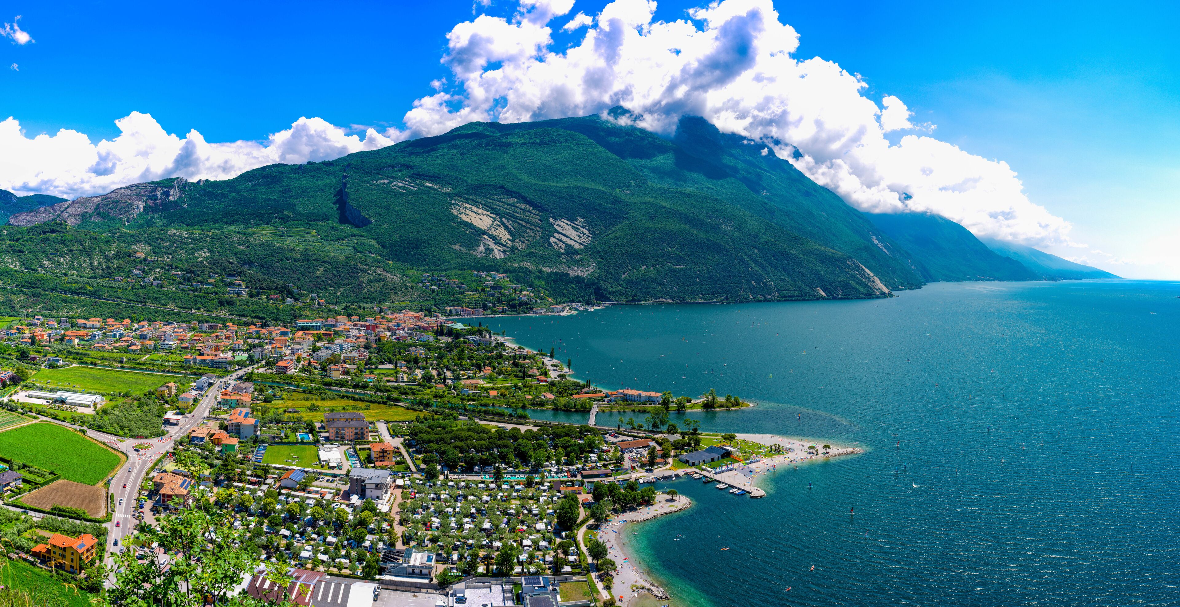 A coastal town with a mountain in the background, a marina, and a clear blue sky.