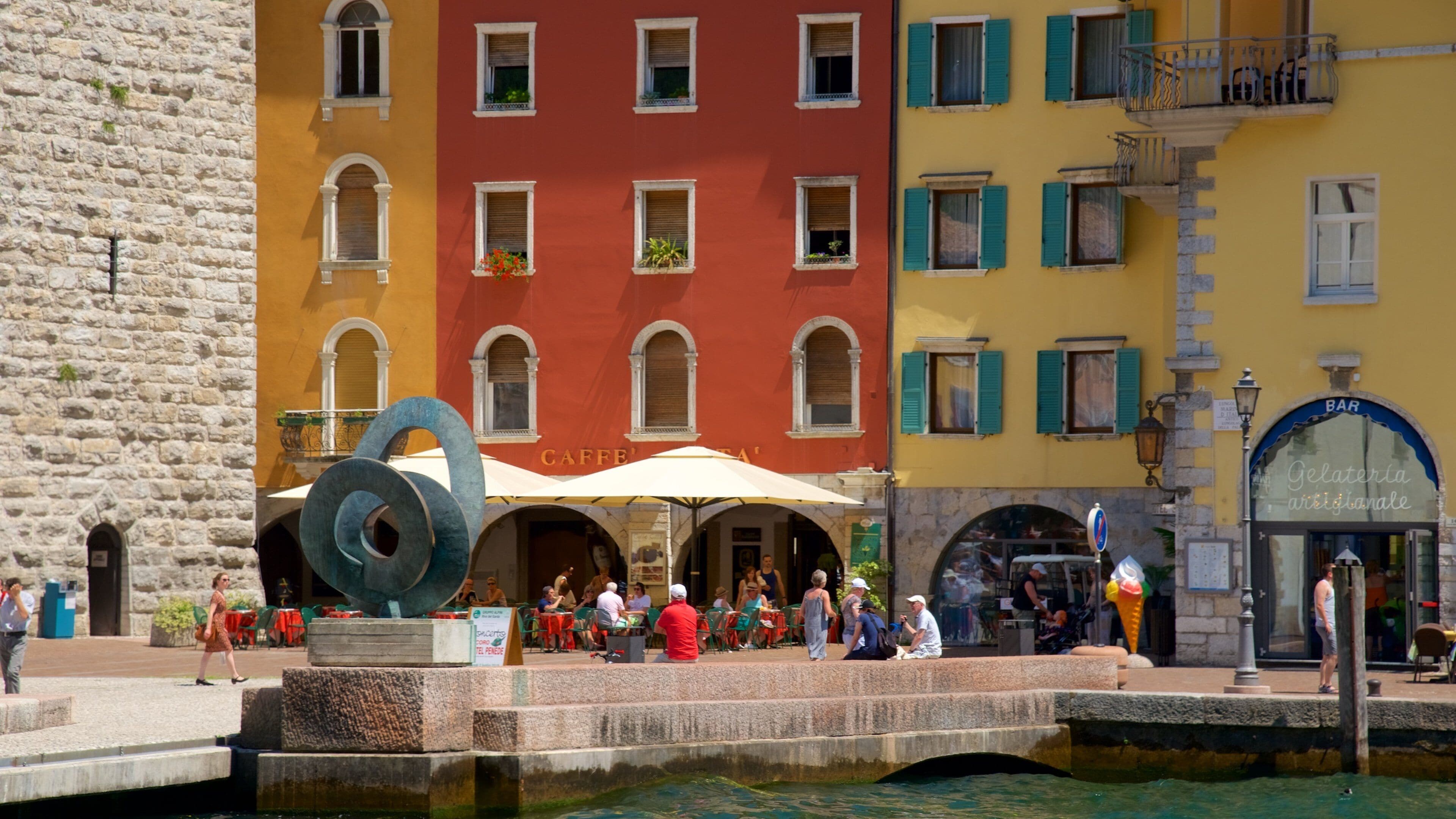 A bustling square with colorful buildings, a fountain, and outdoor seating areas.