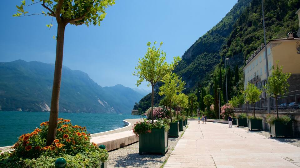 A coastal walkway with mountains, a clear blue sky, and a calm sea.