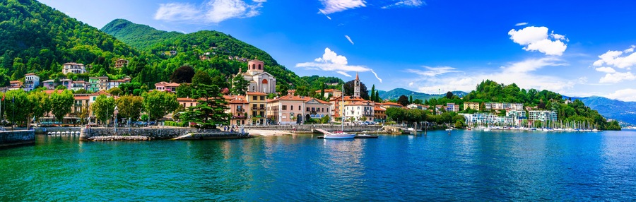 Un pueblo costero con una iglesia destacada, edificios coloridos y un lago azul cristalino.