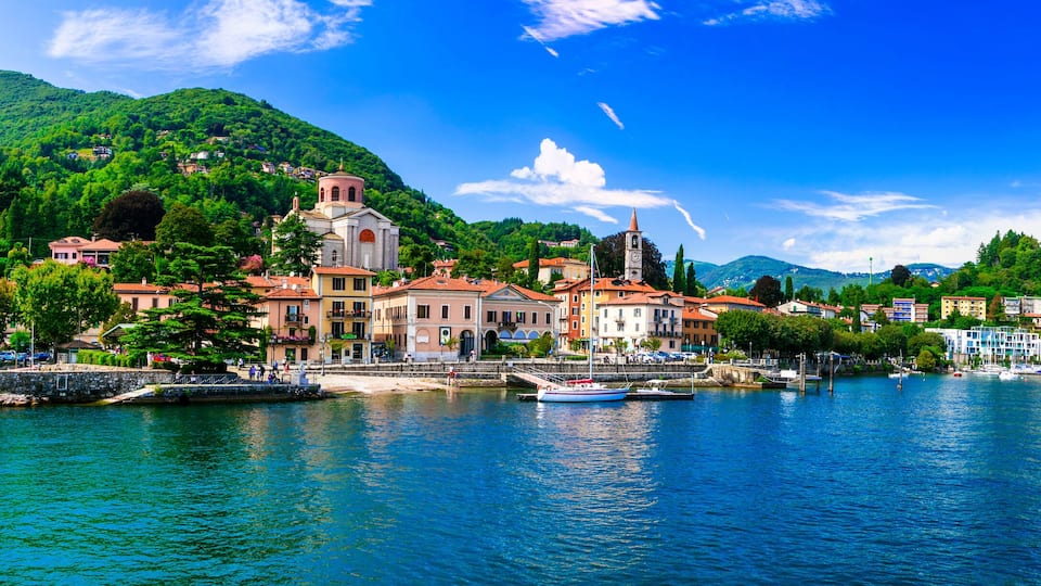 A coastal town with a prominent church, colorful buildings, and a clear blue lake.