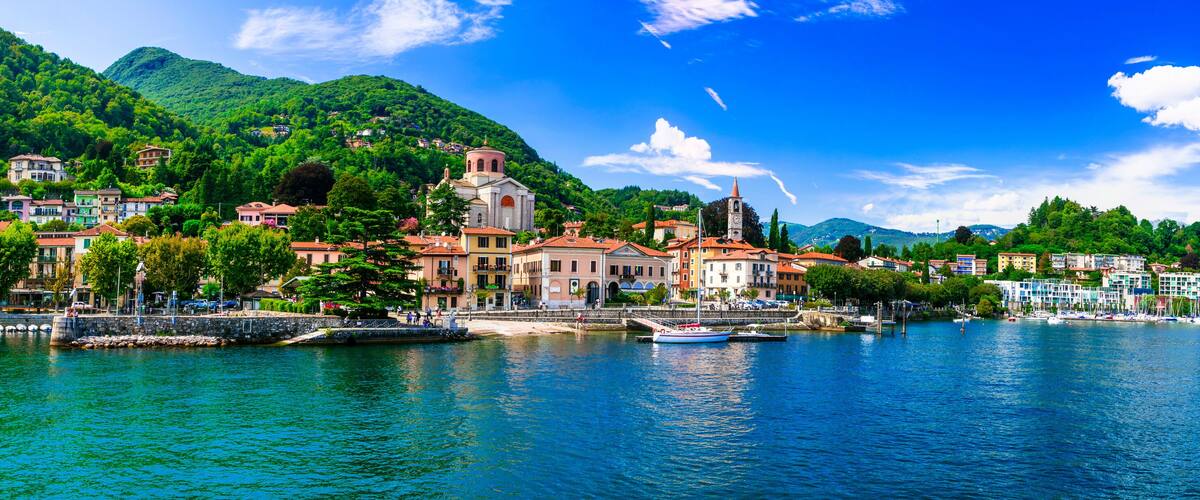 A coastal town with a prominent church, colorful buildings, and a clear blue lake.