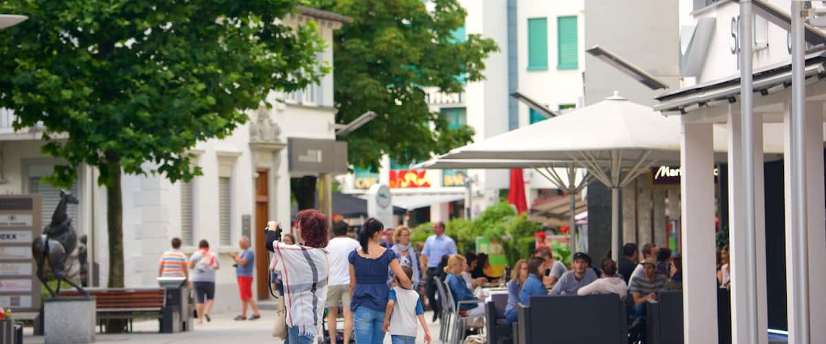 A bustling urban street with pedestrians, outdoor seating, and a mix of modern and classical architecture.