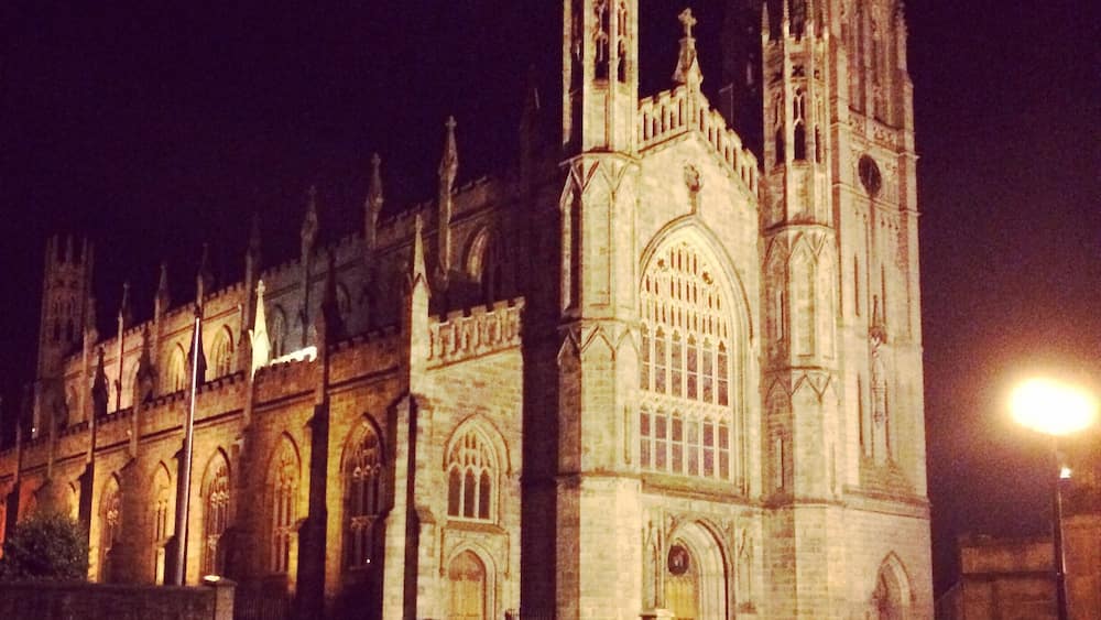 A Gothic-style cathedral with tall spires and arched windows, illuminated at night.
