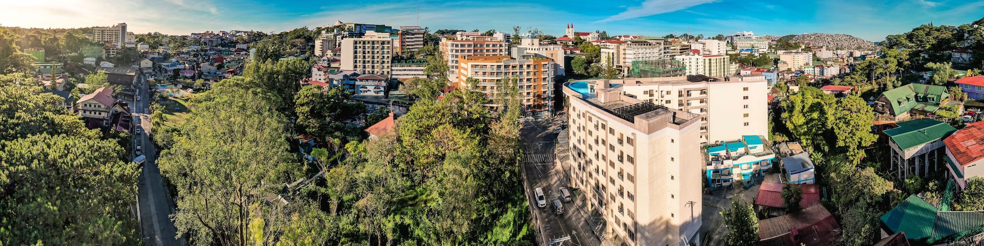 Baguio City, Philippines - Jan 16, 2024: Panoramic aerial of Midrise condominium buildings and Happy Glenn Loop near the core dowtown area at morning.