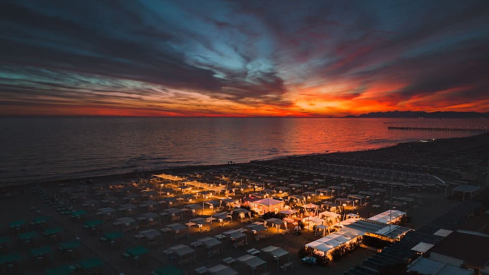 A coastal area with tents and a pier extending into the water during sunset.
