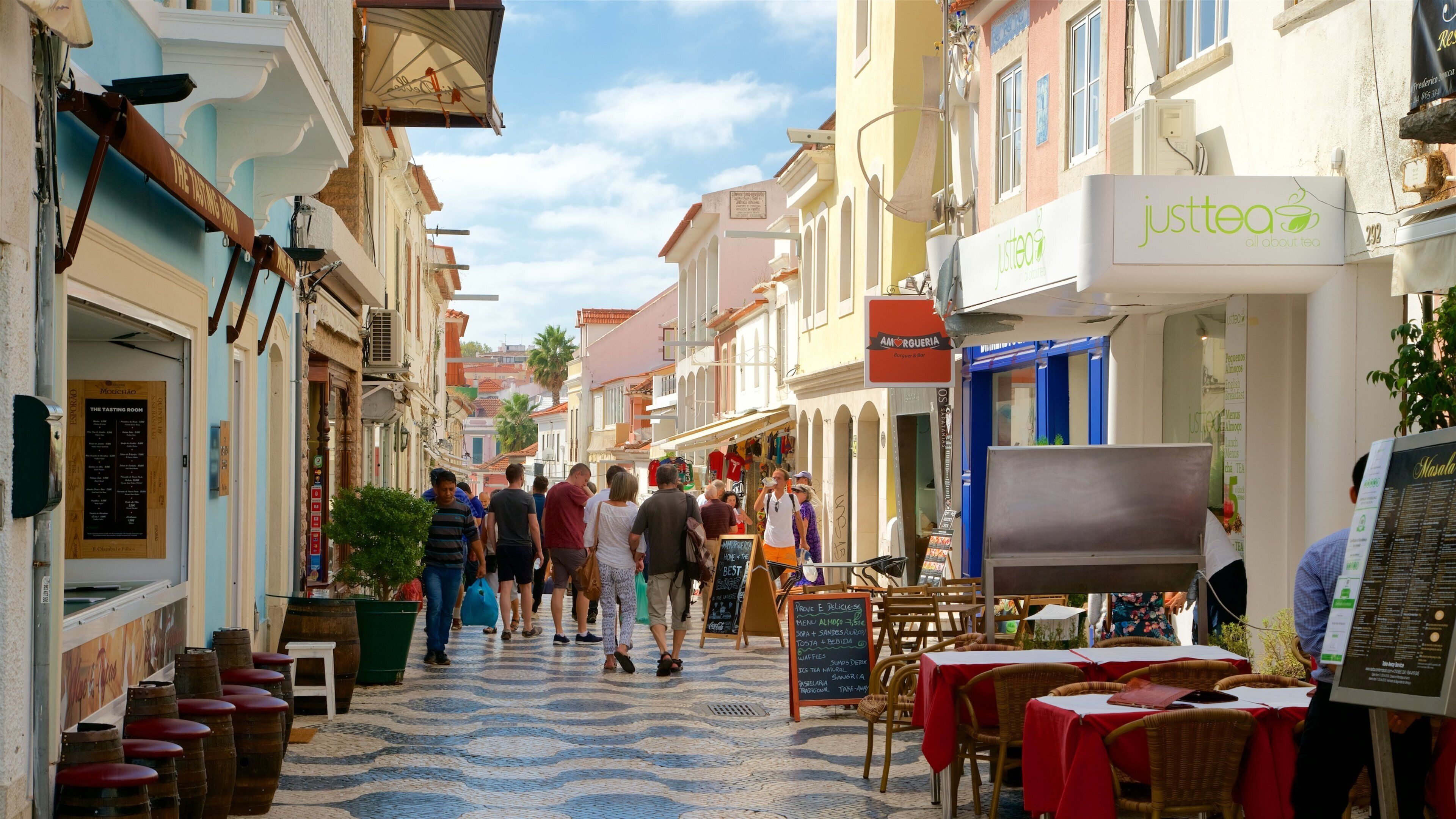 A bustling street with shops and cafes, including 'Justtea' and 'Amorguera'.