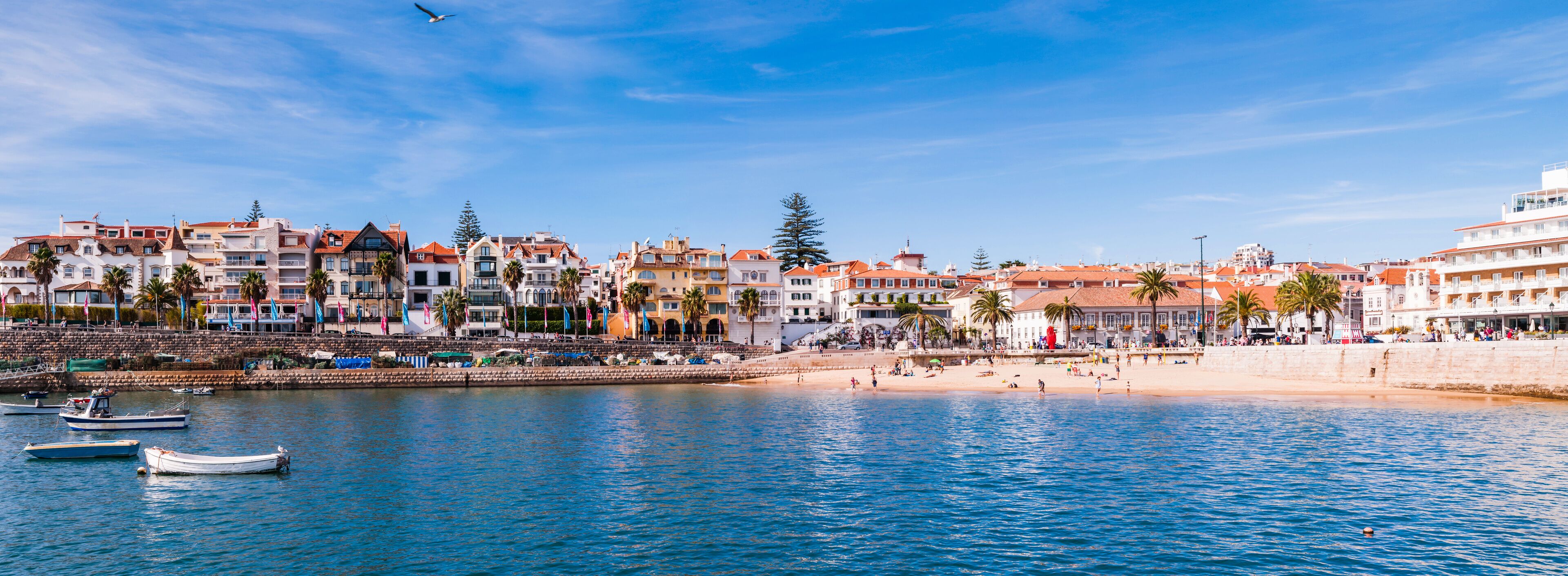A coastal town with colorful buildings, a sandy beach, and boats in the water.