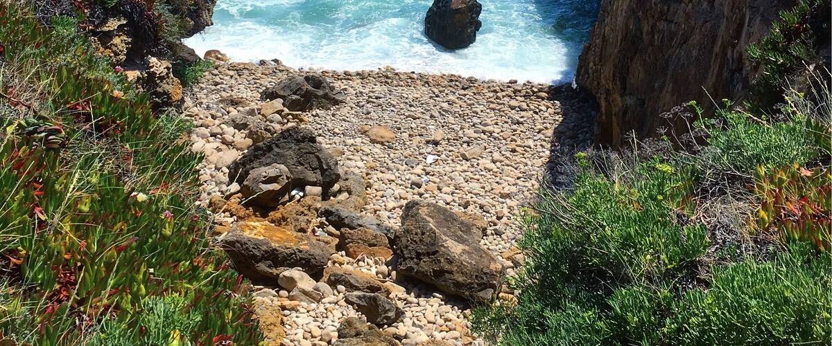 Eine Küstenlandschaft mit felsigen Klippen, einer steinigen Küste und dem Meer.