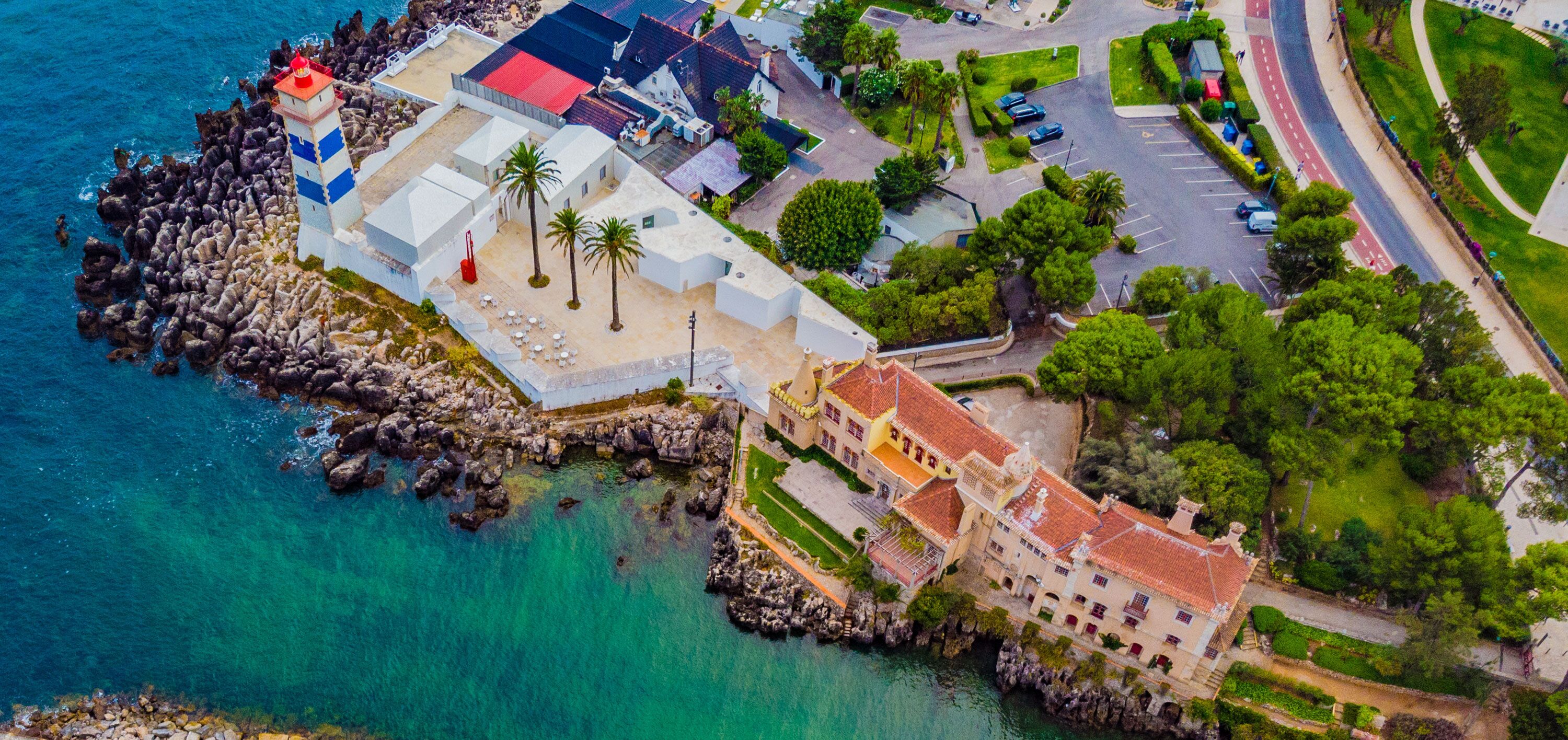 A coastal town with a lighthouse, rocky shoreline, and a mix of residential and commercial buildings.