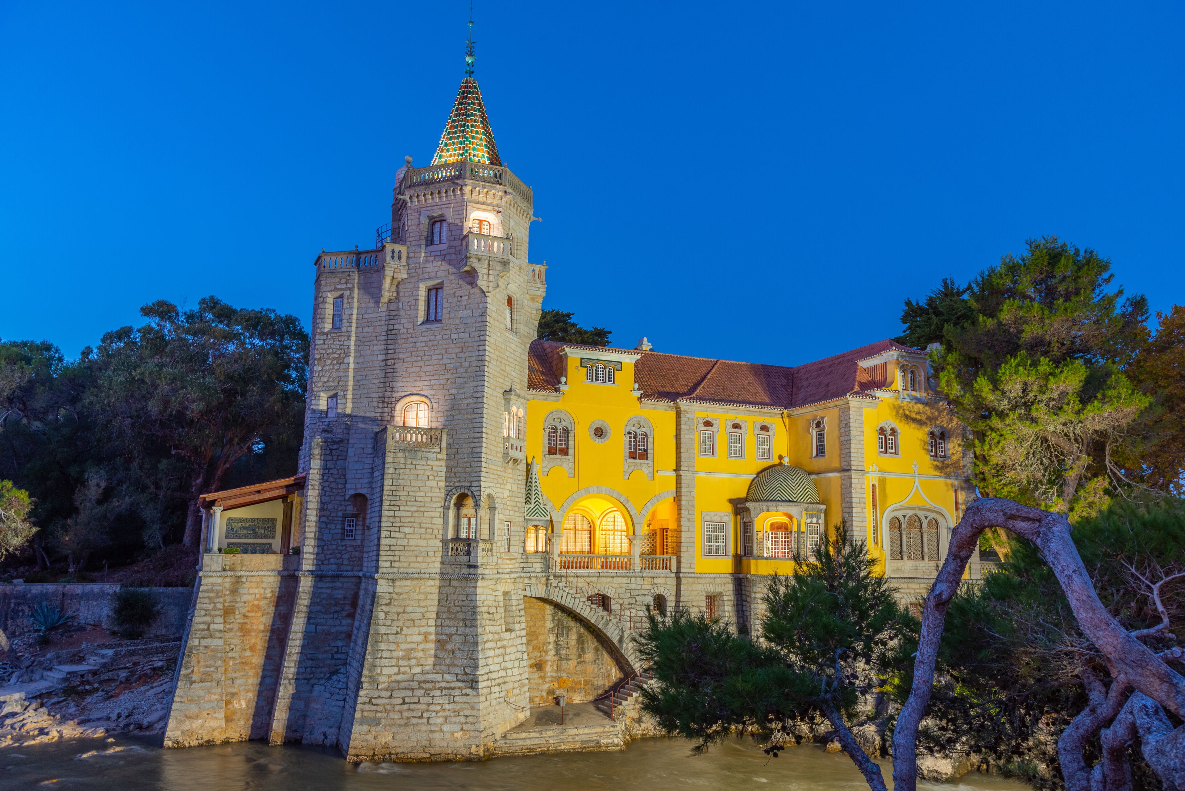 A historic building with a tower, a bridge, and a river.