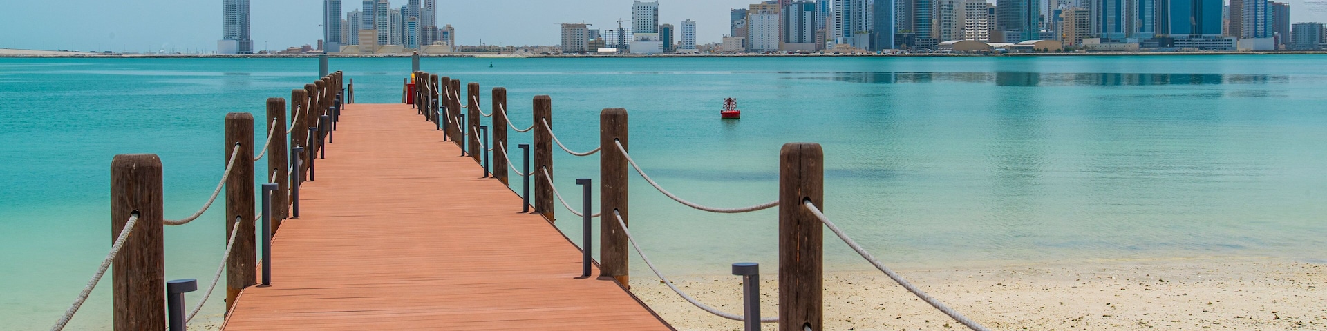 Manama which includes general coastal views, a city and a sandy beach