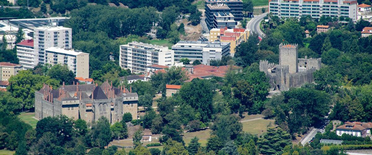 A castle surrounded by modern buildings and lush greenery.