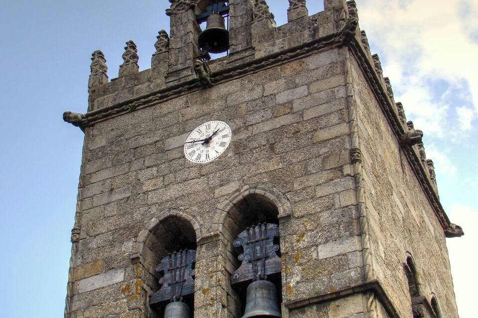A historic tower with a clock, arched windows, and a weather vane.