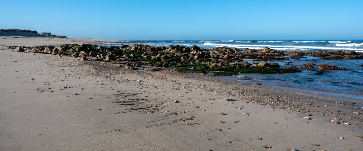 A rocky shoreline with waves crashing onto the beach.
