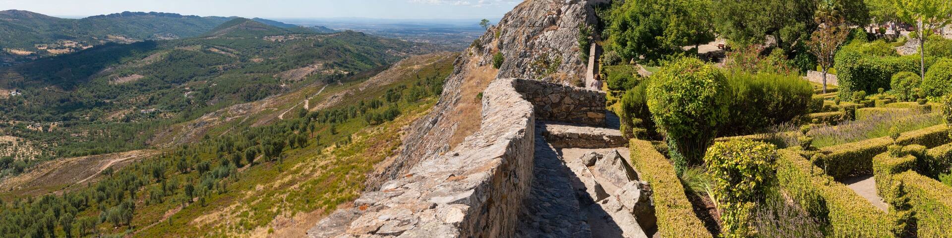 A historic stone castle on a hill with a view of the surrounding landscape.