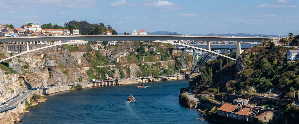 A bridge spanning a river with a town on one side and a rocky hillside on the other.