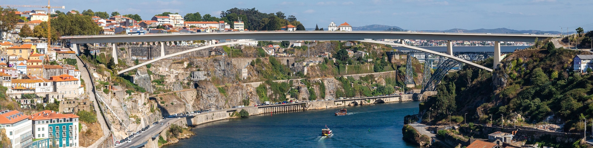 A bridge spanning a river with a town on one side and a rocky hillside on the other.