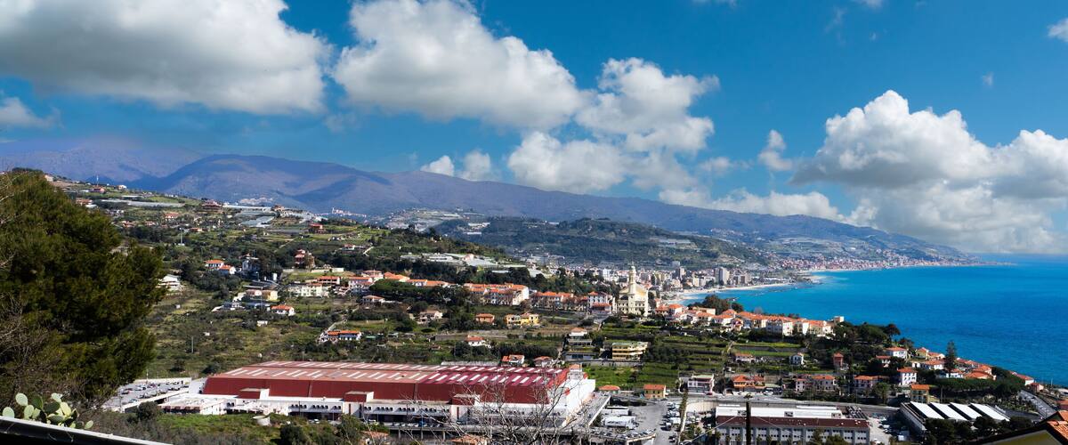 A coastal town with a prominent church, a red-roofed building, and a clear view of the sea.