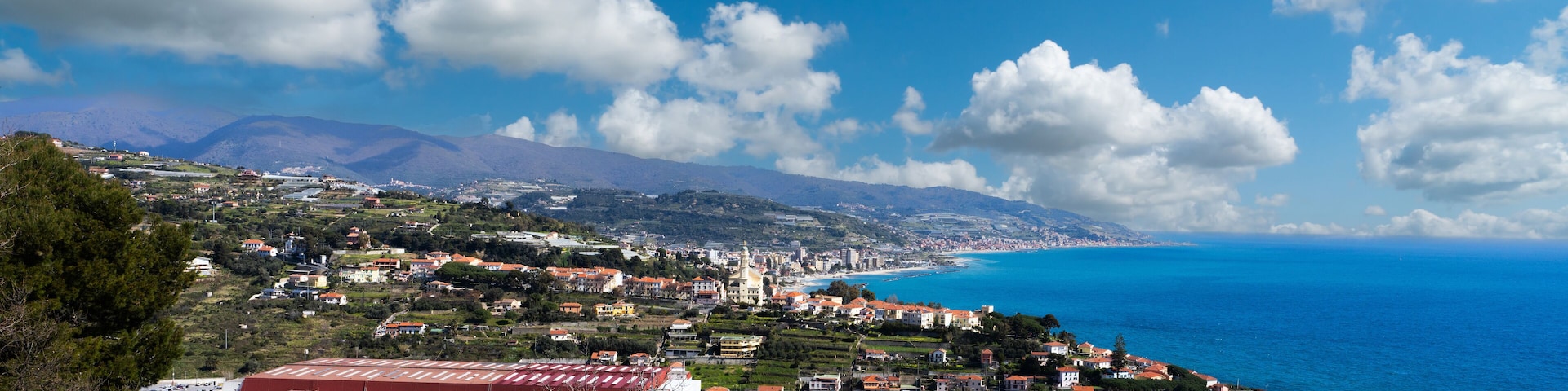 A coastal town with a prominent church, a red-roofed building, and a clear view of the sea.