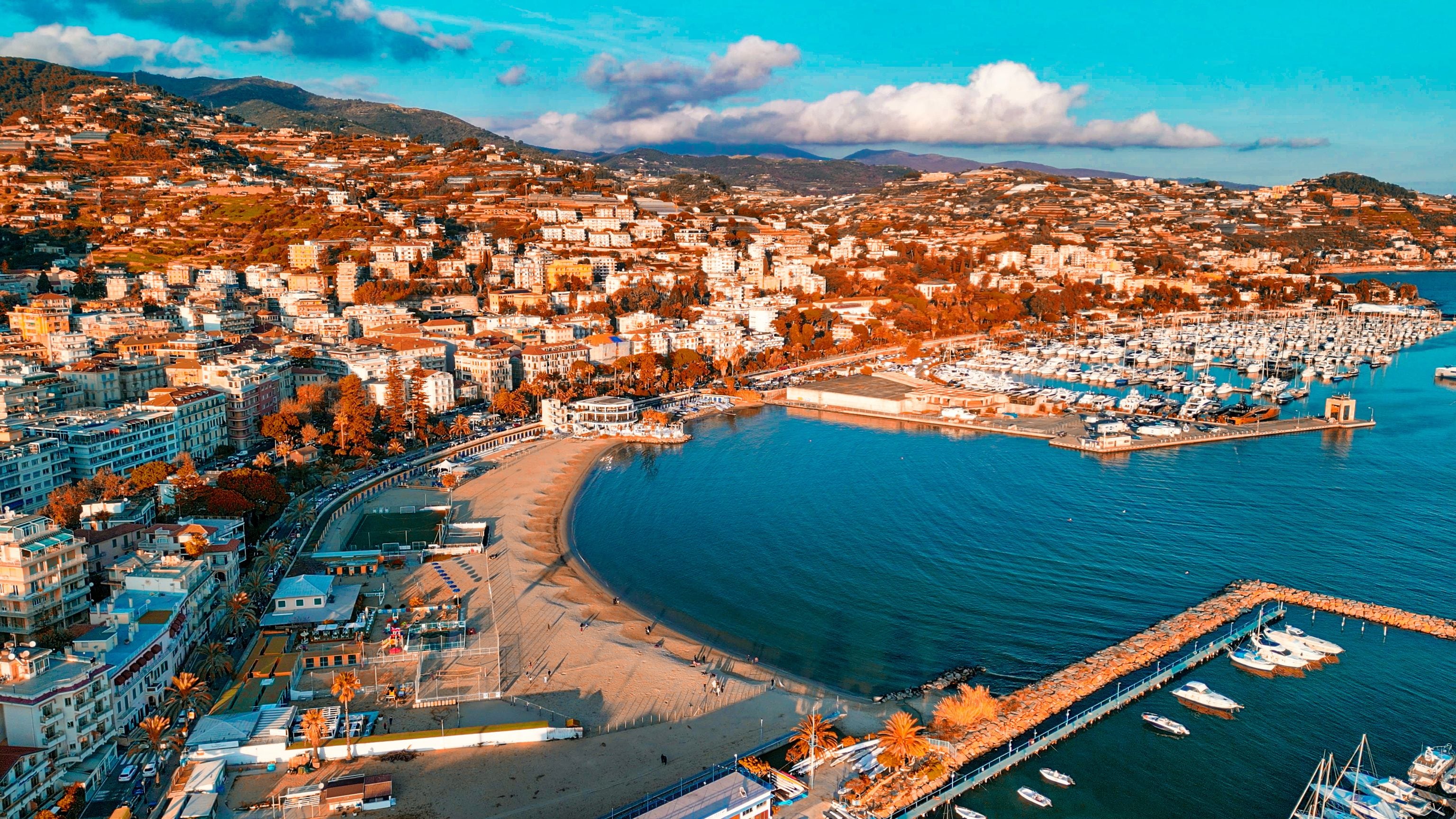A coastal cityscape with a marina, dense urban buildings, and a beach.