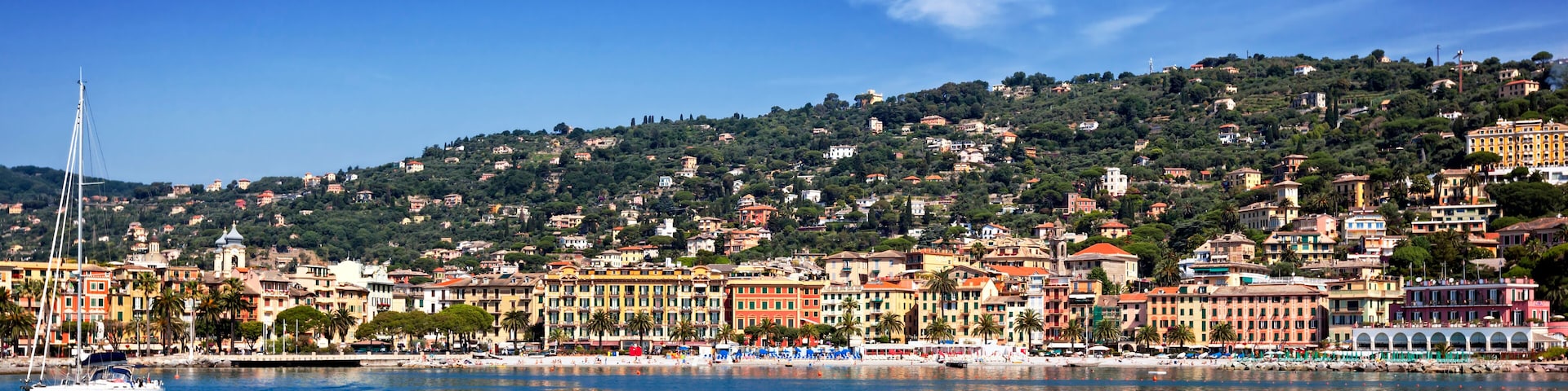 A coastal town with colorful buildings, a marina, and a hillside with scattered houses.