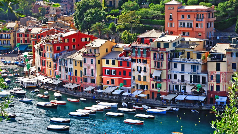 A coastal town with colorful buildings and numerous boats docked along the waterfront.