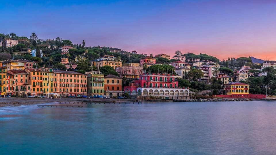 A coastal town with colorful buildings and a calm sea at sunset.
