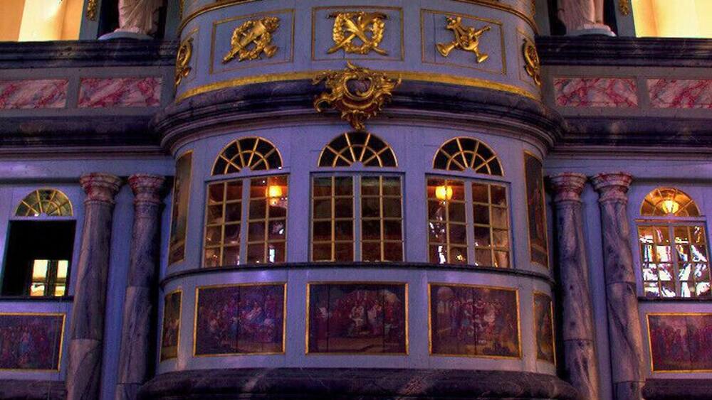 An ornate building with a curved facade, large windows, and statues.