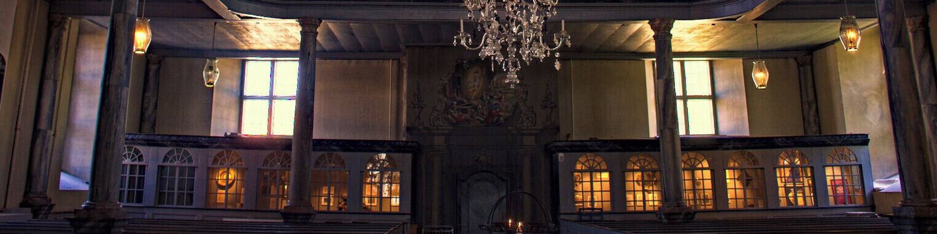 An ornate interior with a large chandelier, high ceilings, and classical architecture.
