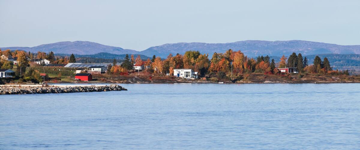 A lakeside town with houses, a dock, and autumn-colored trees.