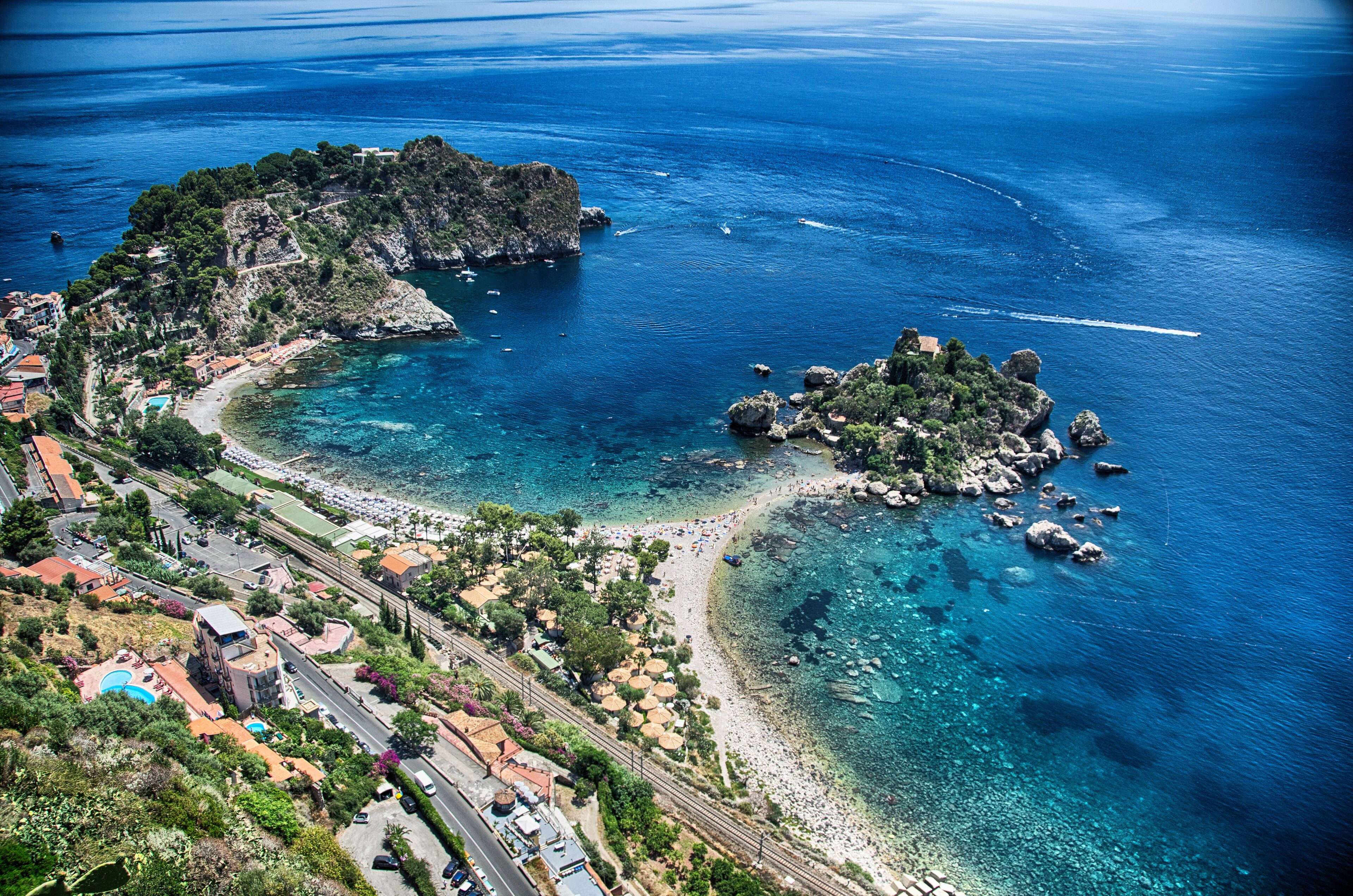 Un pueblo costero con playa, afloramientos rocosos y aguas azul turquesa.