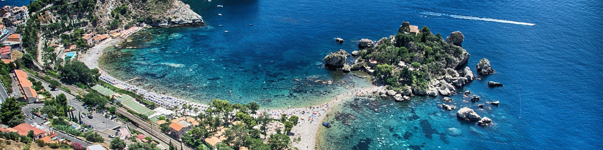 Un pueblo costero con playa, afloramientos rocosos y aguas azul turquesa.