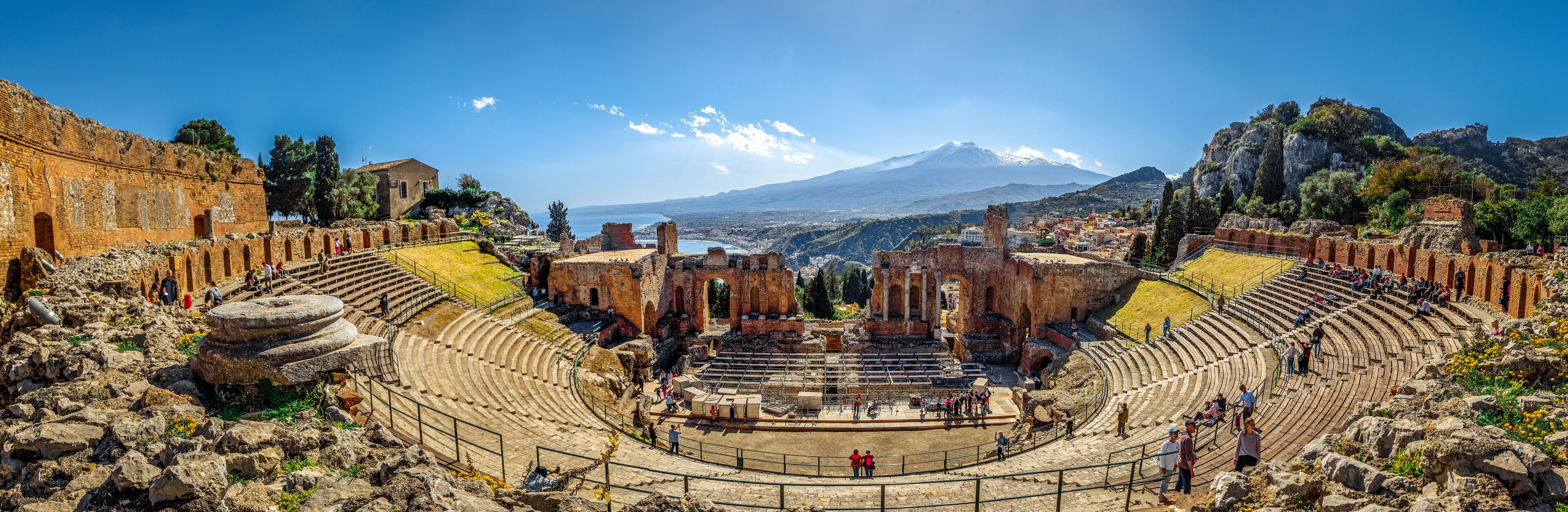 An ancient amphitheater with ruins and a mountain in the background.