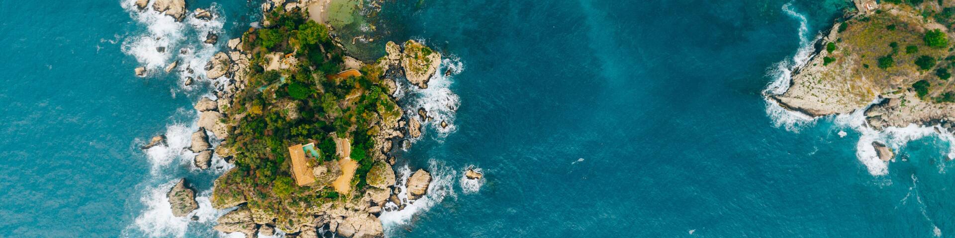 Aerial view of charming coastal Mediterranean small town on Sicily island, Taormina. Beaches of Taormina and south Italy.Travel destination, vacation in Italy concept.Aerial landscape of Bella Isola