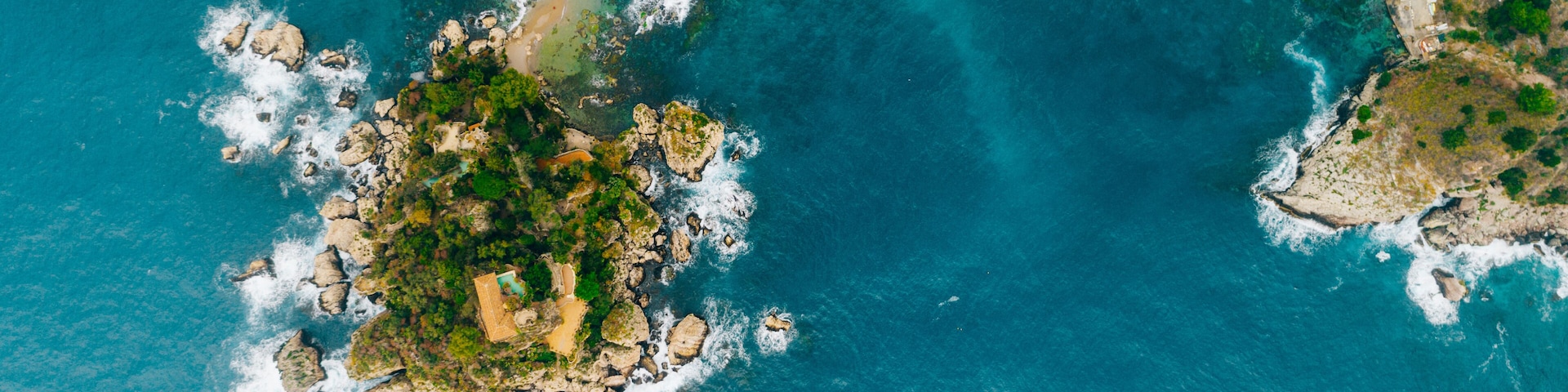 Aerial view of charming coastal Mediterranean small town on Sicily island, Taormina. Beaches of Taormina and south Italy.Travel destination, vacation in Italy concept.Aerial landscape of Bella Isola