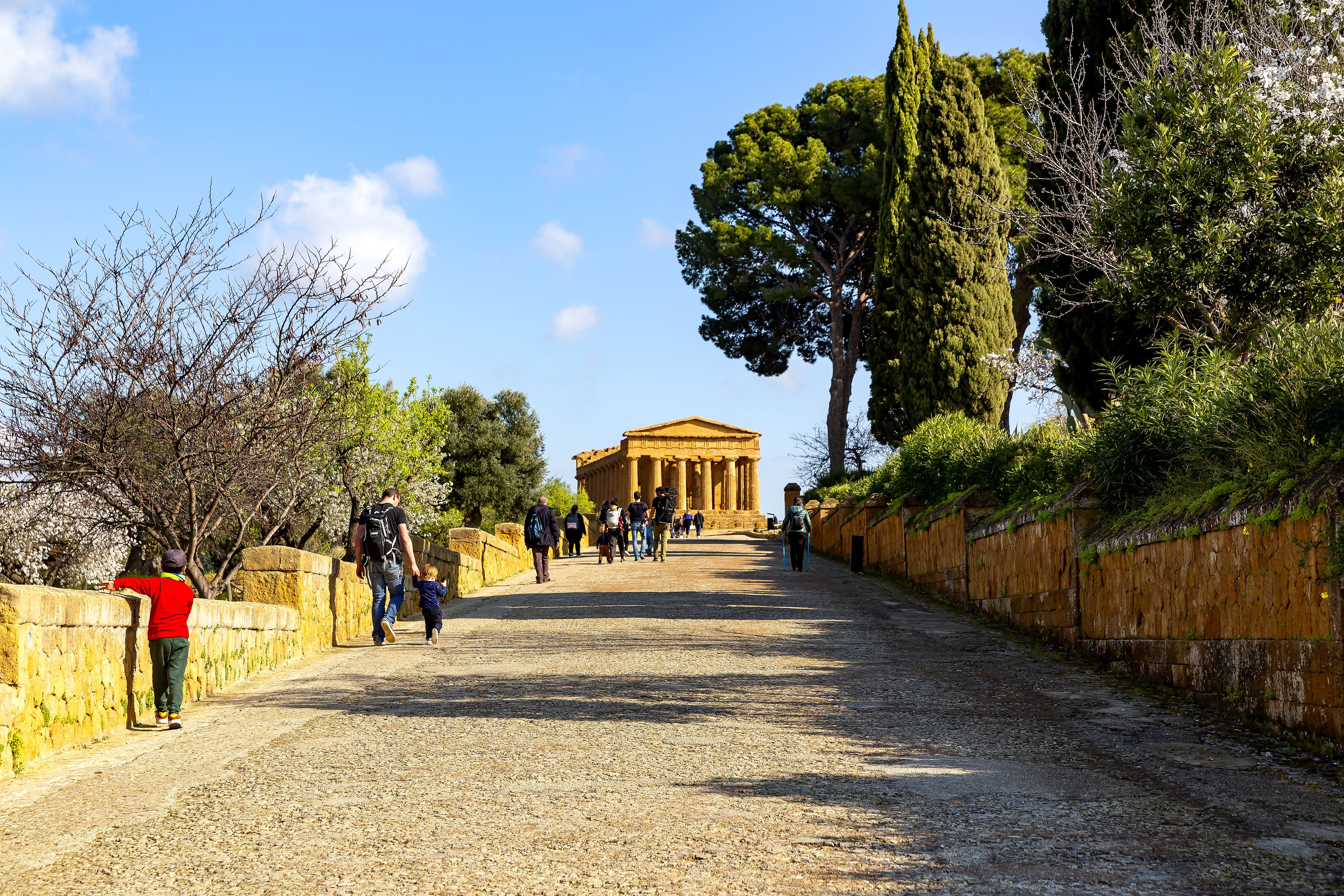 Un sitio histórico con antiguas columnas, un camino empedrado y visitantes.