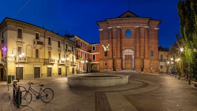 A historic square with a central fountain, surrounded by classical buildings and a prominent church with a bell tower.