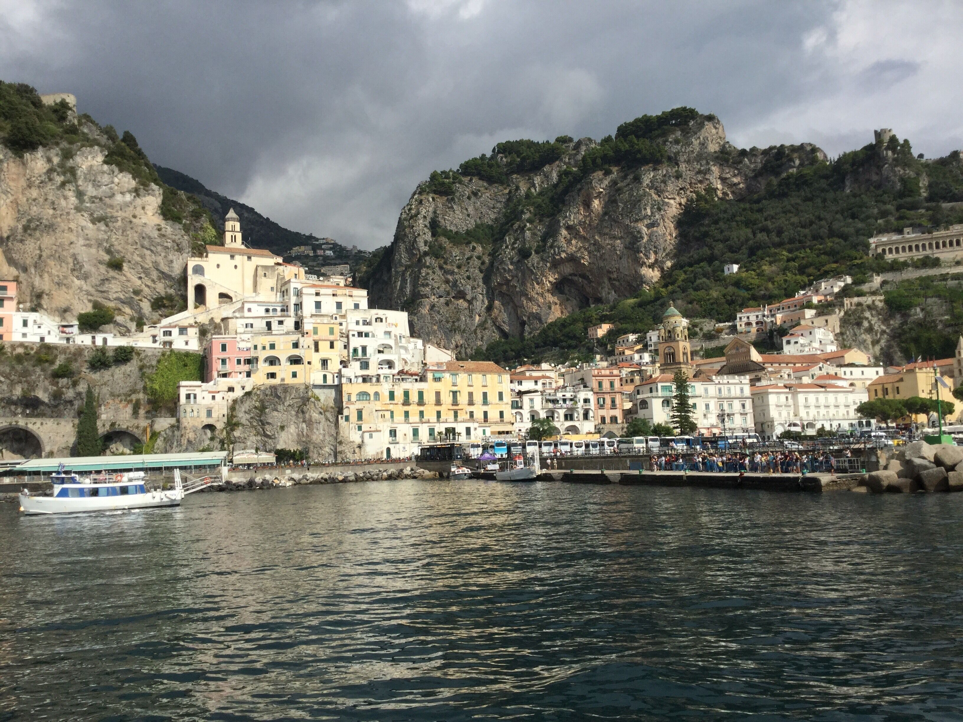 A coastal town with colorful buildings, a church, and a rocky mountain backdrop.
