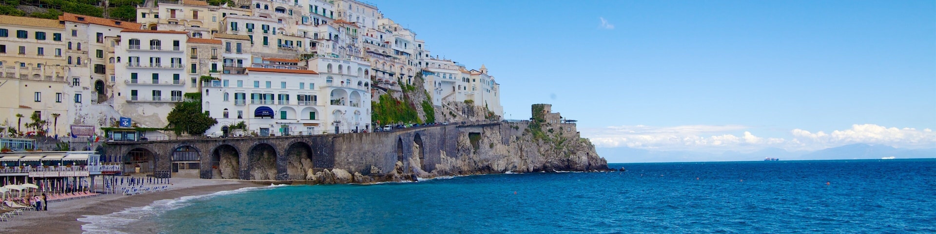 A coastal town with white buildings, a beach, and a rocky cliff.