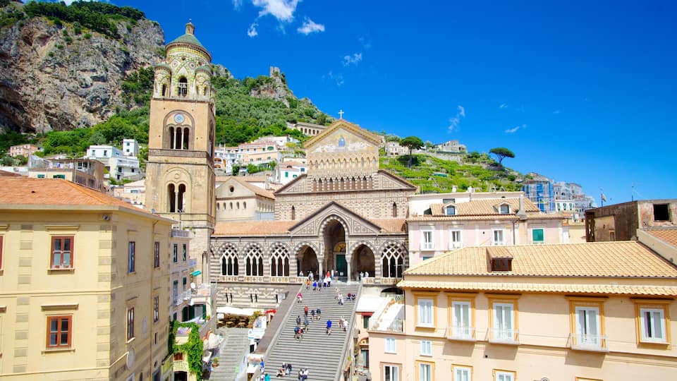 A historic church with a bell tower and a hillside town.