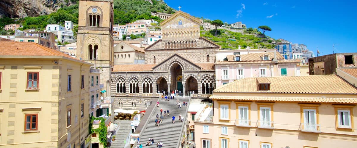 A historic church with a bell tower and a hillside town.
