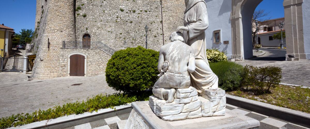 A stone building with a statue of a woman and child in front.