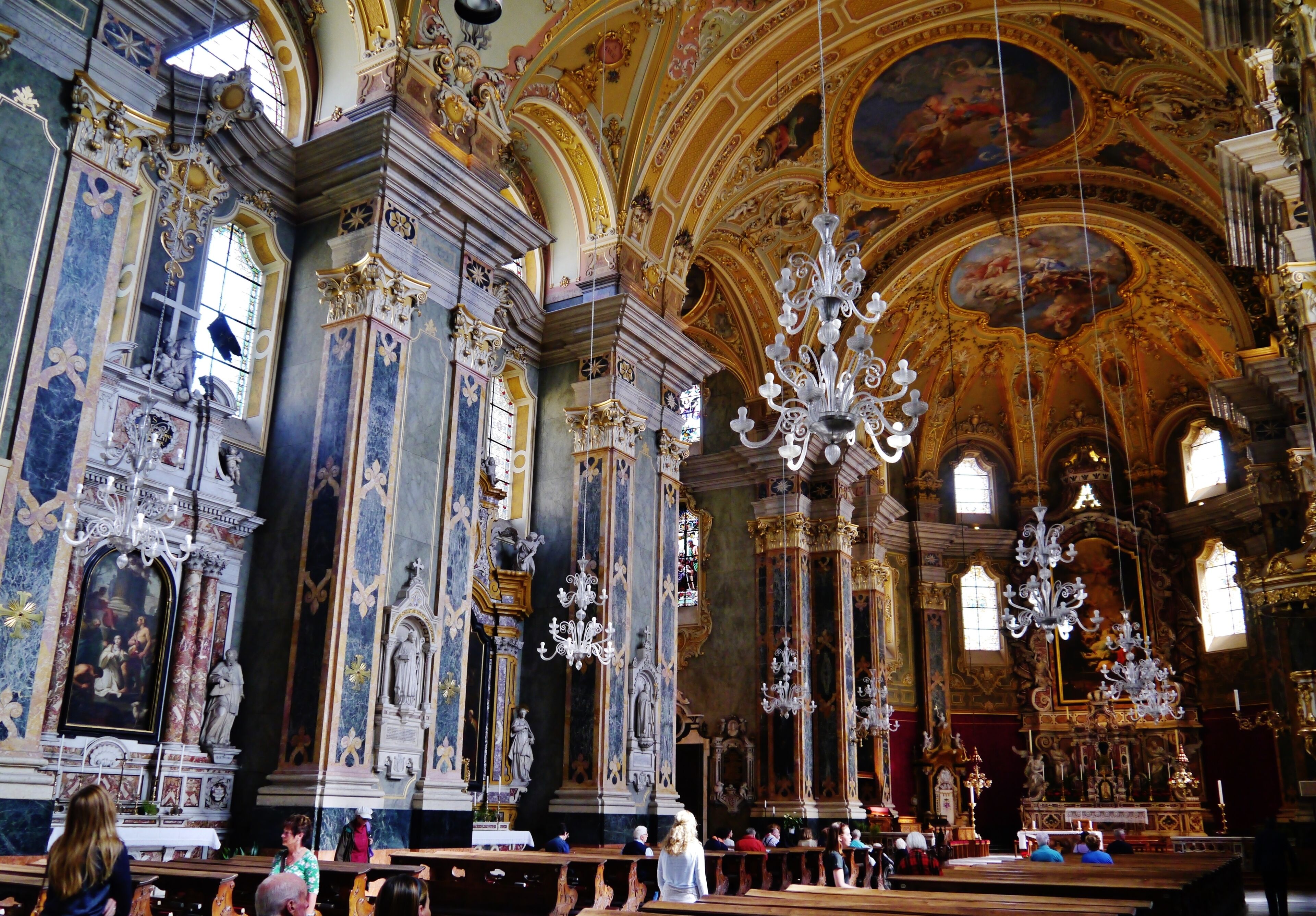 An ornate church interior with detailed frescoes, gold accents, and chandeliers.