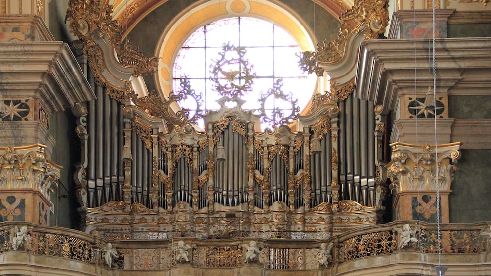 An ornate organ with intricate carvings and a large circular window above it.