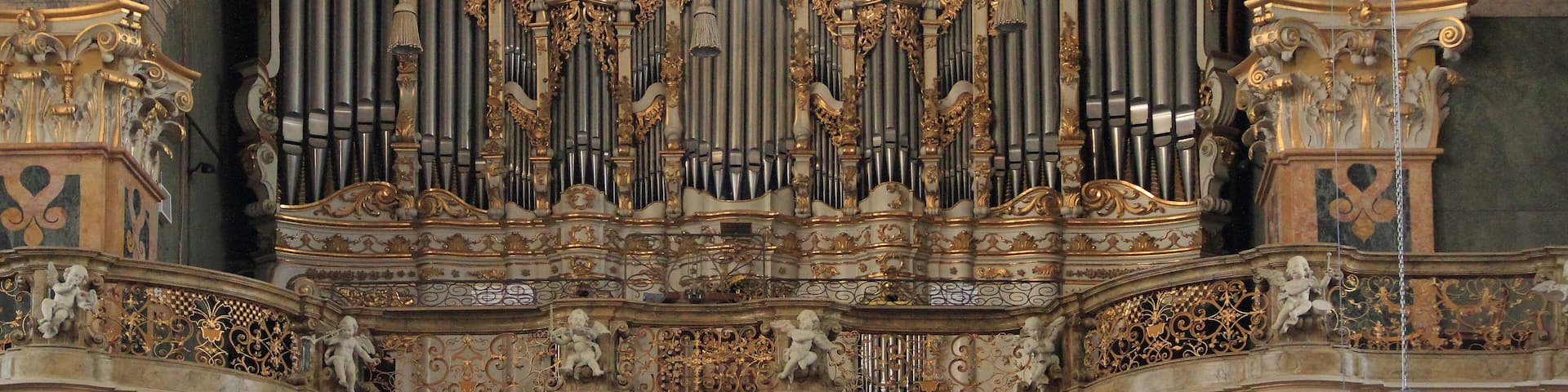 An ornate organ with intricate carvings and a large circular window above it.