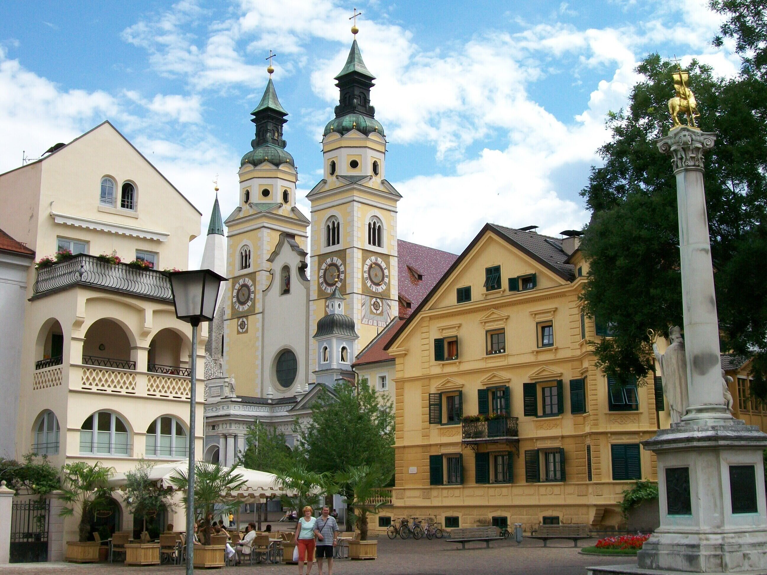Una plaza histórica con una iglesia, una estatua y edificios tradicionales.