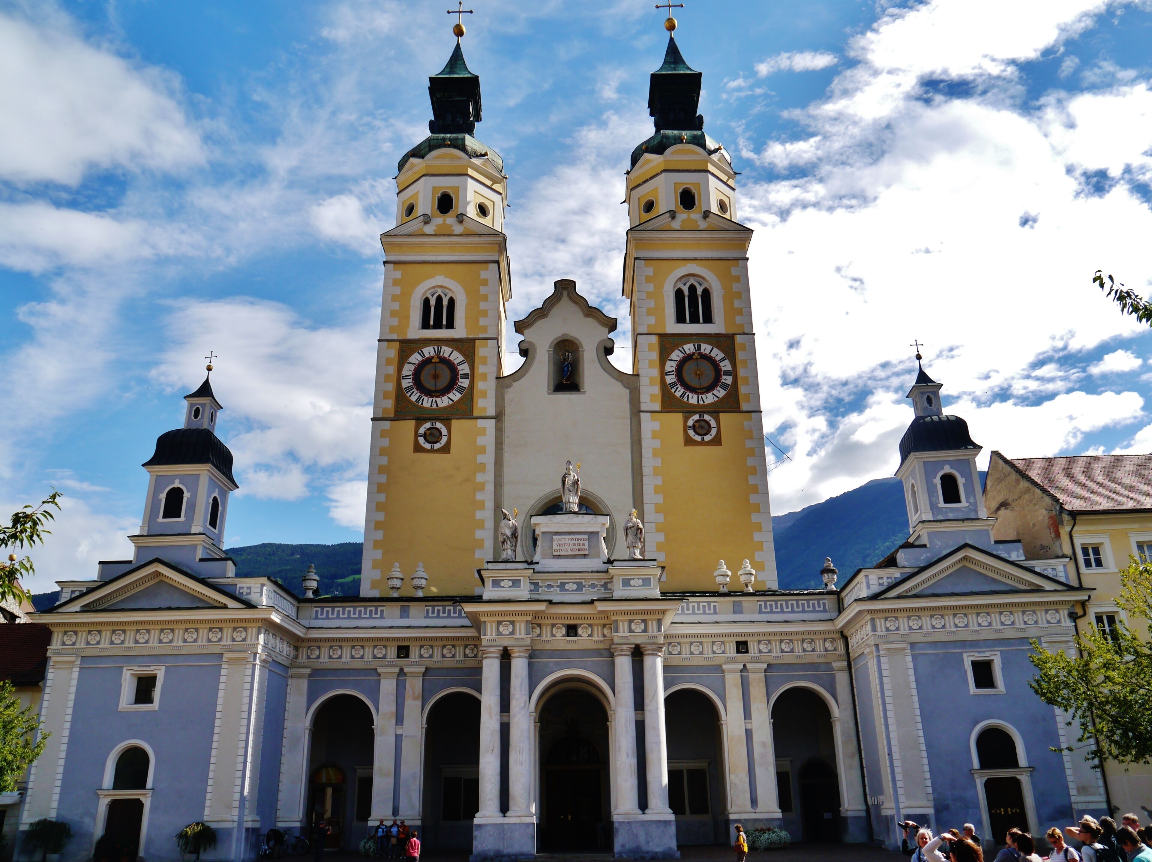 A church with two towers, a large clock, and statues in front.